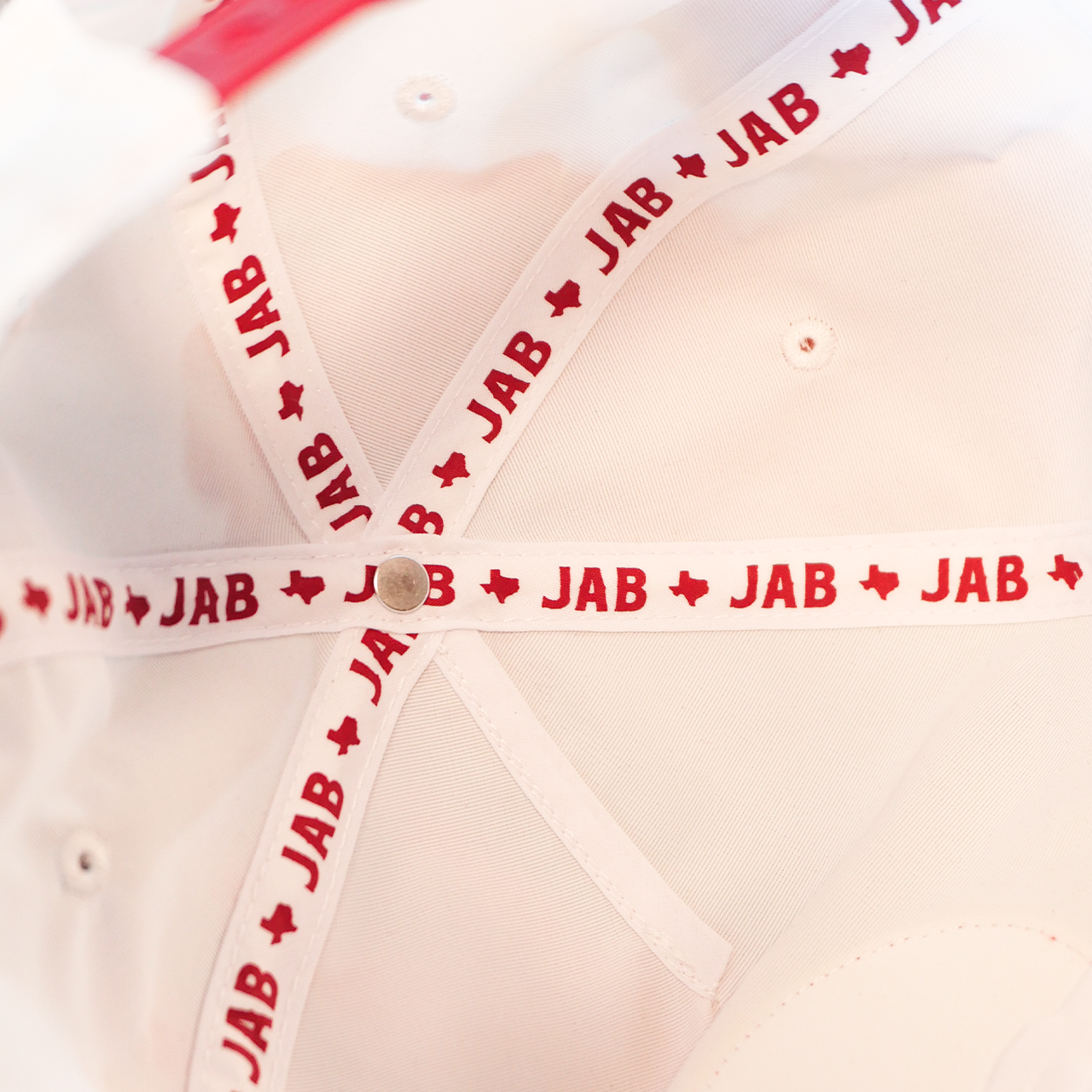 Ribbon or tape with repeating ’JAB’ text printed in red.